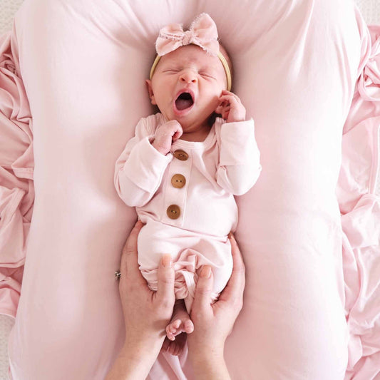 Newborn baby in a pink outfit with a bow headband