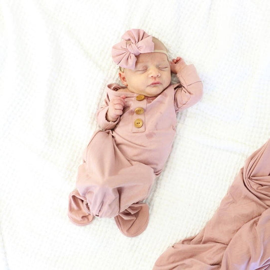 Newborn baby in a pink outfit with a matching headband