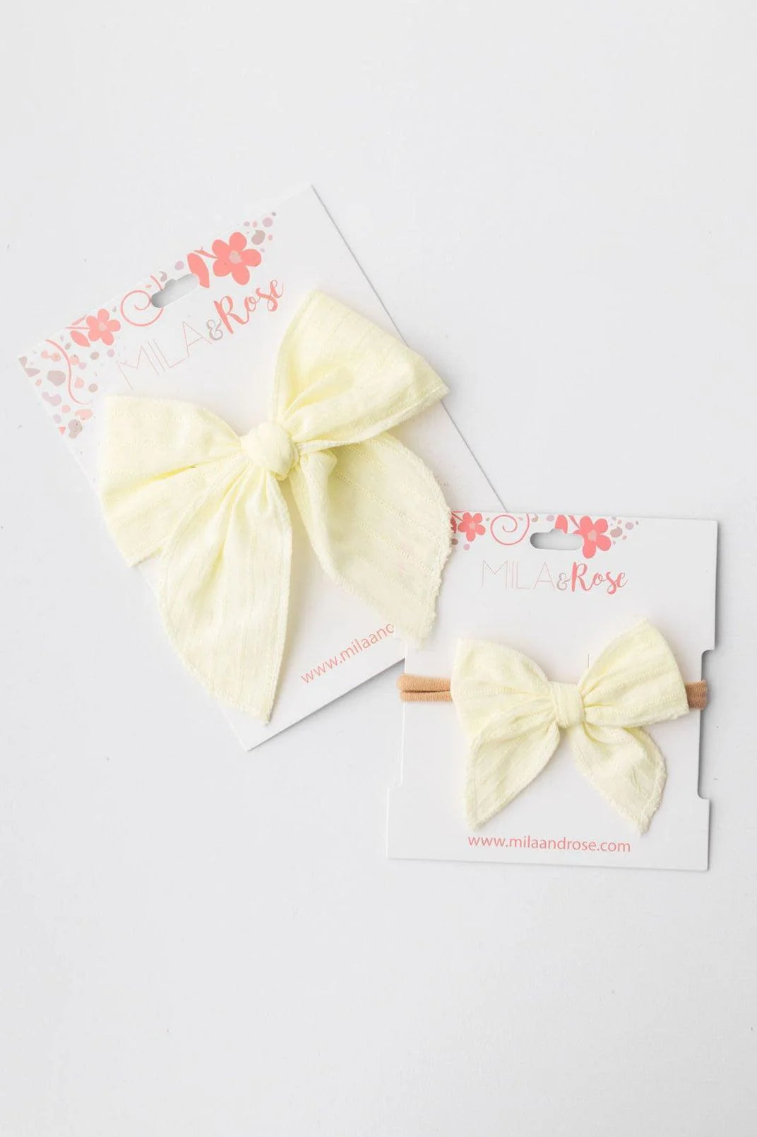 Two yellow hair bows on white cards with floral designs