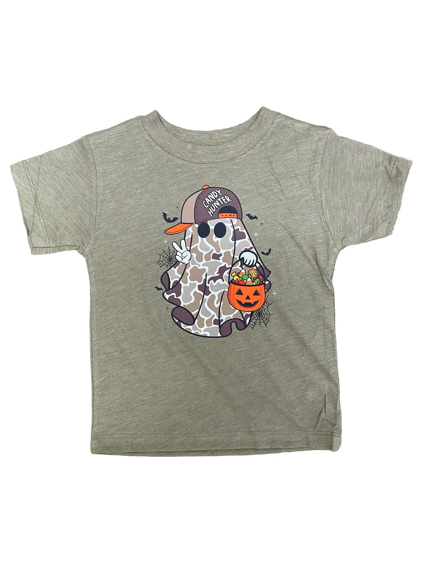 A toddler's heather olive green short-sleeve t-shirt with a Halloween graphic of a ghost wearing a camouflage cap and holding an orange pumpkin bucket, laid flat on a brown wood background.