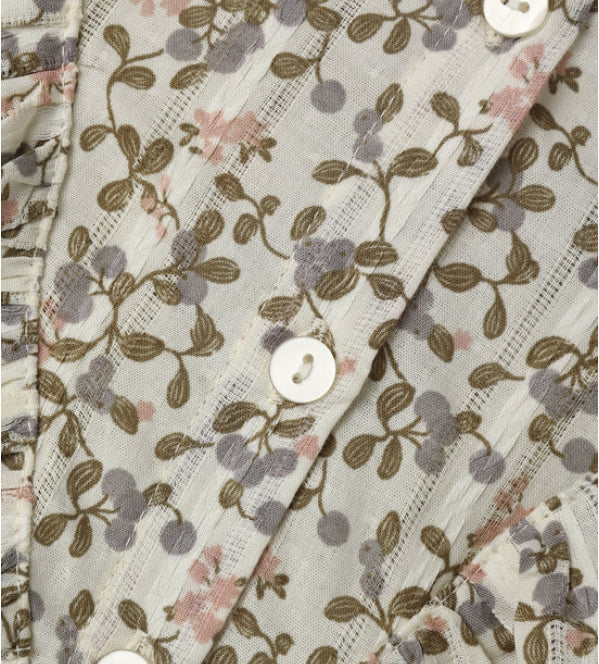 Close-up of a lightweight button-front garment fabric with a delicate floral and berry print in muted pink, gray, and olive-brown on a warm off-white background.