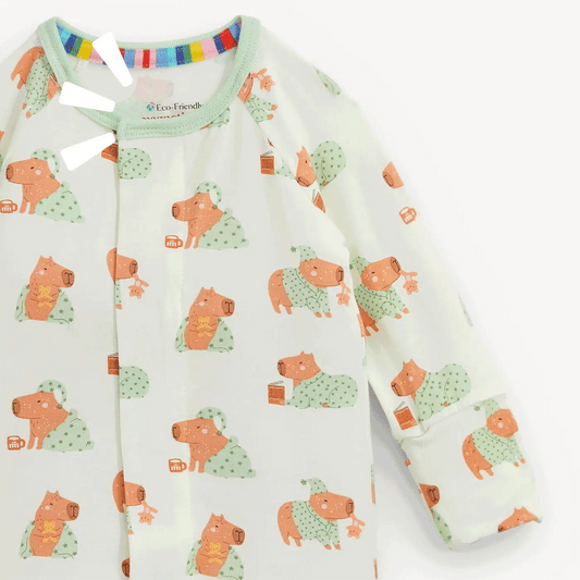 A long-sleeve baby sleep sack by Too Looody, featuring a cute capybara print in orange and green on a white background.
