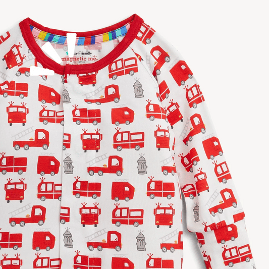 A close-up of a baby long-sleeve top with a white base and an all-over print of red fire trucks and gray fire stations, featuring a red ribbed collar.