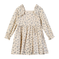 A long-sleeve babydoll dress with a beige base and a delicate blue and green floral print, featuring a ruffled collar and smocked waist.