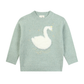 A light sage green knit sweater featuring a large white fluffy swan appliqué on the chest, with small gold embroidered stars and swirls.
