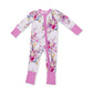 A baby long-sleeve footed one-piece sleeper with a pink zipper, featuring a white background with a colorful floral print and solid pink cuffs and foot cuffs.