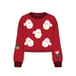 A red long-sleeve cropped sweater with an all-over Santa Claus face pattern, ribbed crew neck, cuffs, and hem, plus small holiday-themed patches on both sleeves, shown on a plain white background.