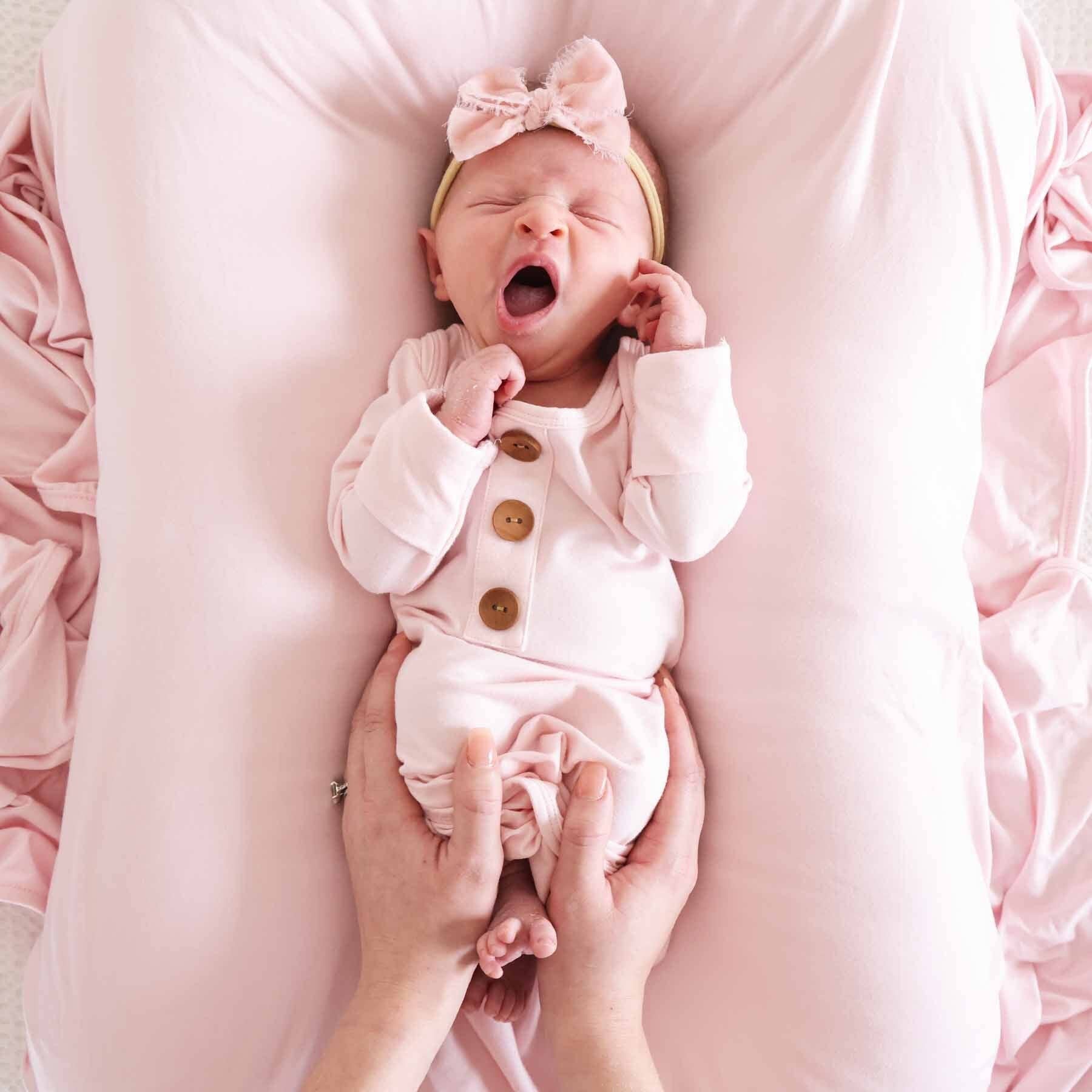 Newborn baby in a pink outfit with a bow headband