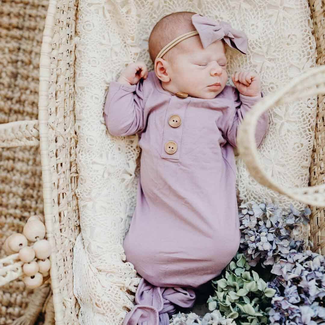 Newborn baby in a purple outfit with a bow