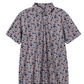 A short-sleeve button-up shirt with an all-over abstract camouflage pattern in navy blue, rust red, and off-white, shown against a plain white background.