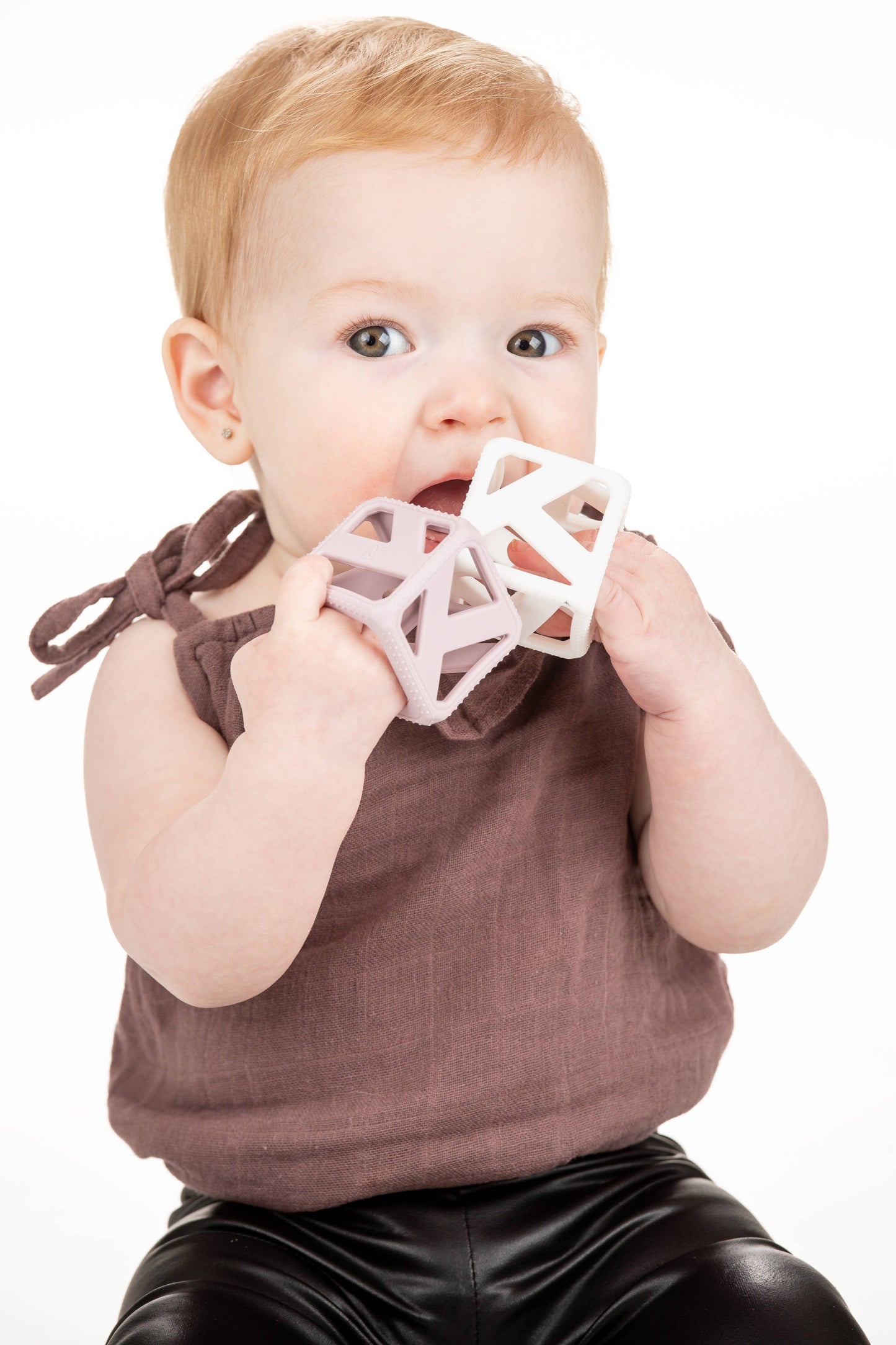 Baby holding a pink geometric teething cube