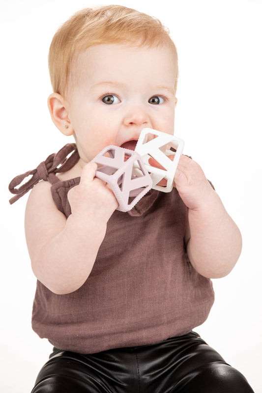 Baby holding a pink geometric teething cube