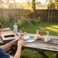 Child playing with a wooden archery set on a wooden table outdoors.