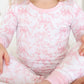 Child wearing a pink and white floral and bow pajama set 
