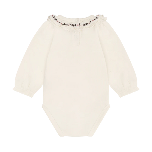 An off-white long-sleeve baby bodysuit with a ruffled collar featuring a delicate black and pink floral pattern, displayed against a solid white background.