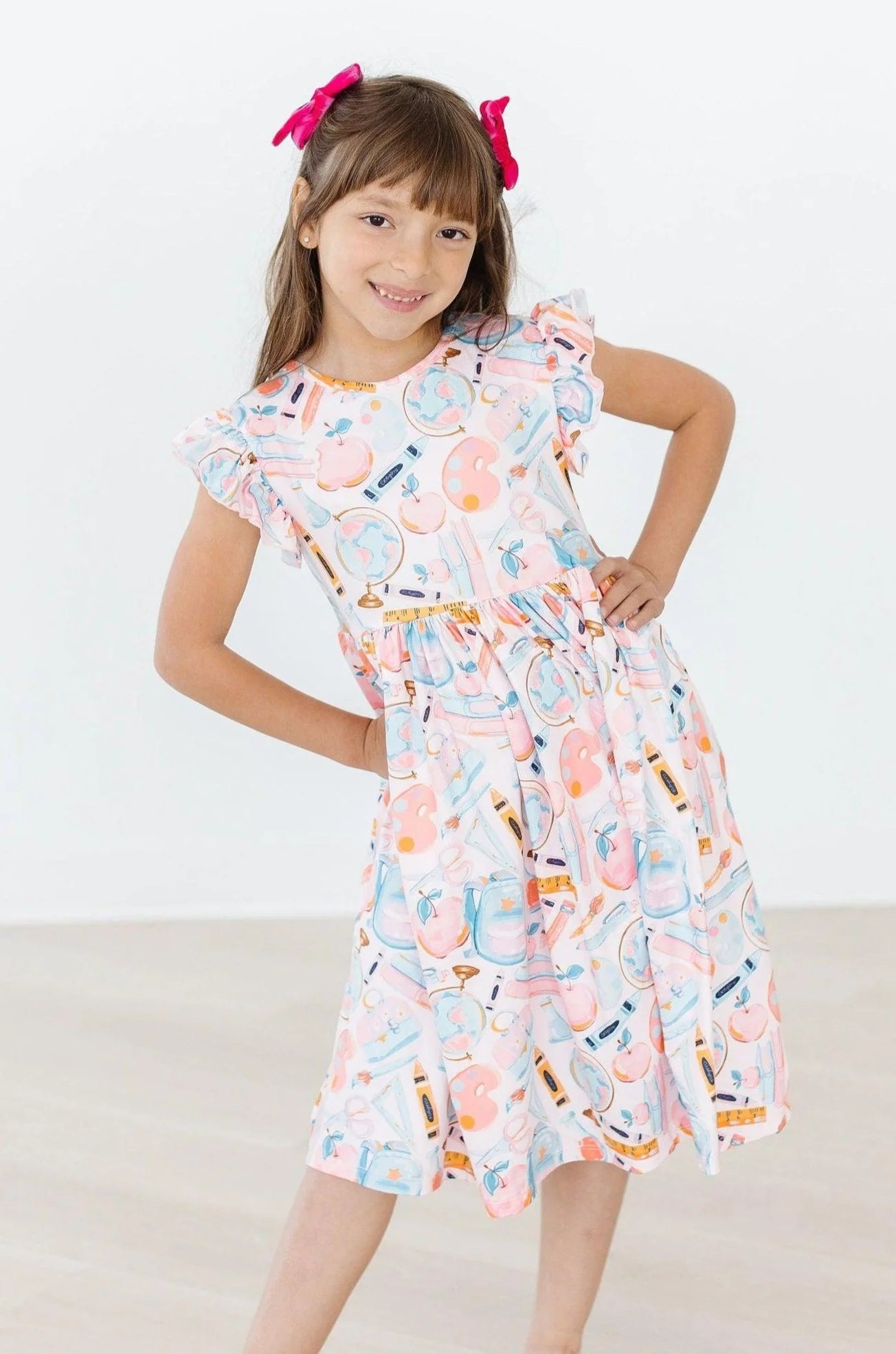 Young girl wearing a colorful dress with a pattern of bottles on a white background