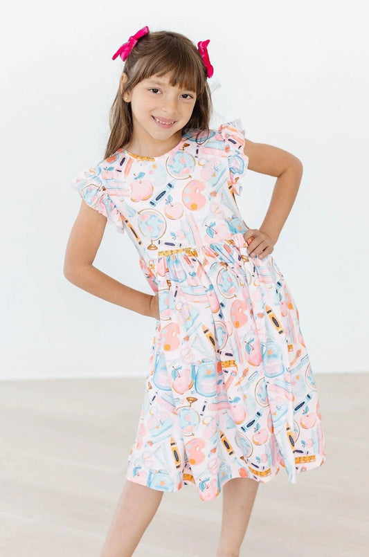Young girl wearing a colorful dress with a pattern of bottles on a white background