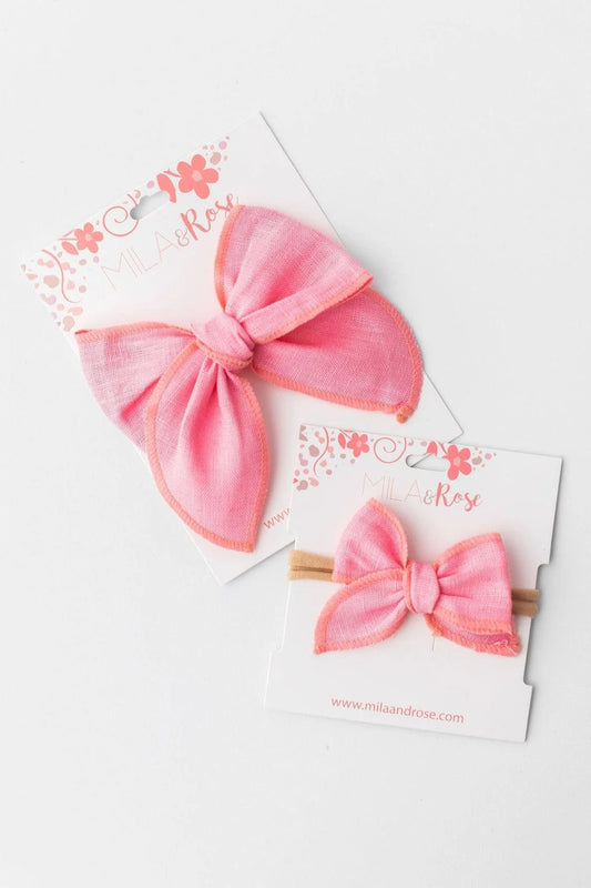 Two pink hair bows on white cards with floral designs.