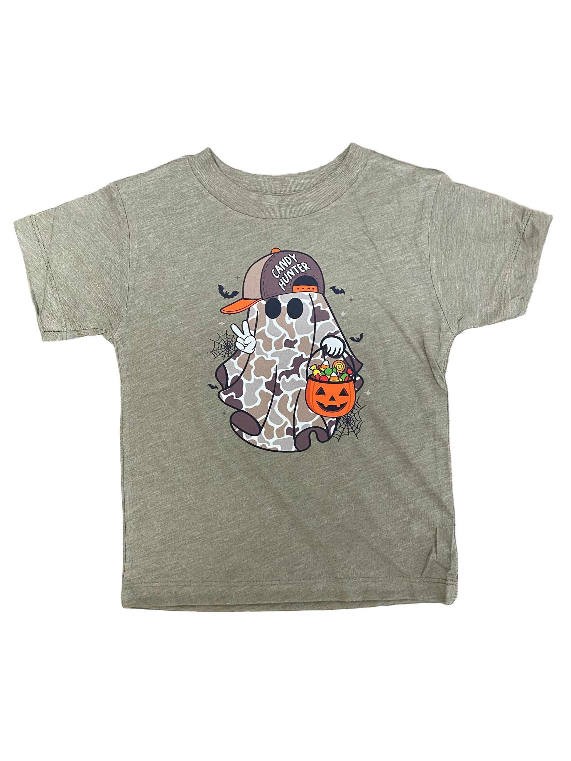 A toddler's heather olive green short-sleeve t-shirt with a Halloween graphic of a ghost wearing a camouflage cap and holding an orange pumpkin bucket, laid flat on a brown wood background.
