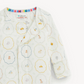 A baby long-sleeve sleep sack by Cozy Friends Magnetic Me, featuring a white base with a colorful pattern of small vehicles, animals, and geometric shapes inside scalloped circles.