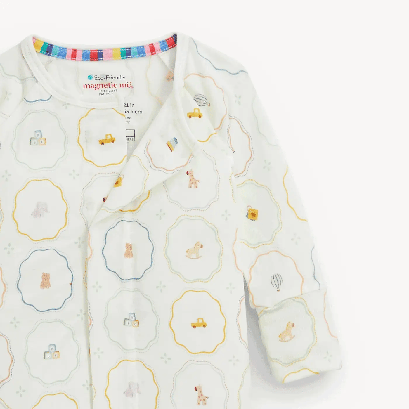 A baby long-sleeve sleep sack by Cozy Friends Magnetic Me, featuring a white base with a colorful pattern of small vehicles, animals, and geometric shapes inside scalloped circles.