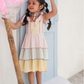 Young girl in a colorful dress holding cotton candy against a light background