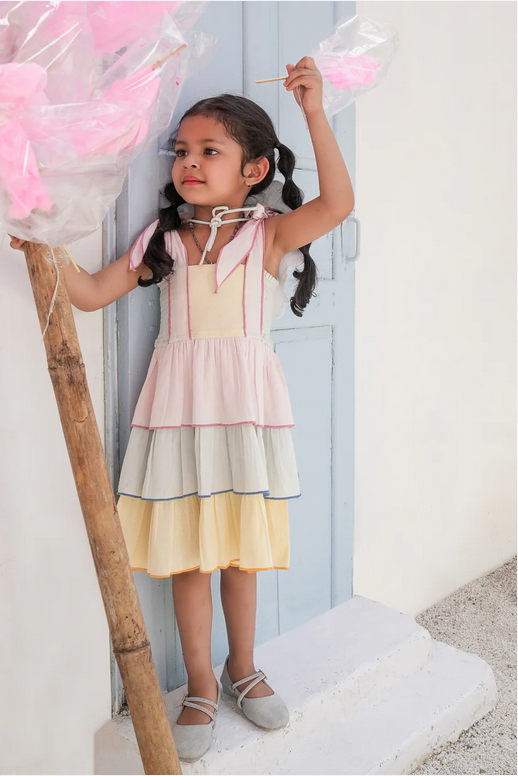Young girl in a colorful dress holding cotton candy against a light background