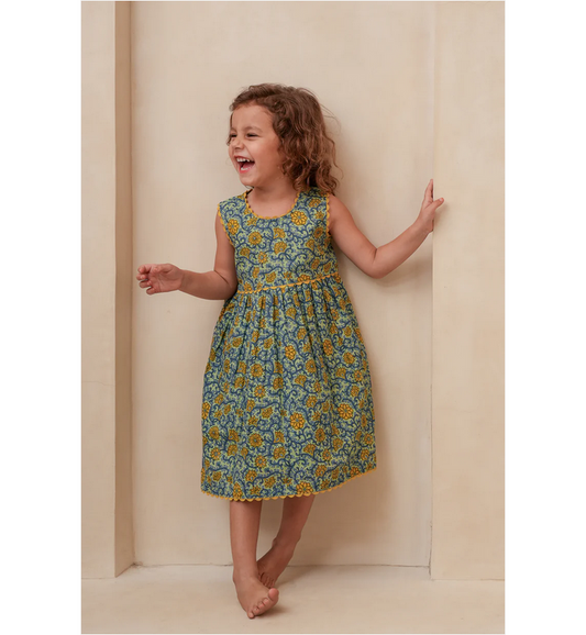 Young girl wearing a floral dress standing against a plain background