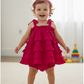 Child wearing a bright pink dress with ruffled layers indoors.