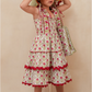 Young girl wearing a floral dress and sun hat against a beige background