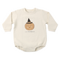 A cream-colored long-sleeve baby bodysuit featuring a cute cartoon pumpkin wearing a black witch hat with the text 'LIL PUMPKIN' printed below it, displayed on a clean white background.