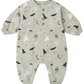 A long-sleeve baby romper in a light sage green color, decorated with a cute Halloween pattern of white ghosts, black bats, brown witch hats, jack-o'-lanterns, spiderwebs, and moons. It features a snap-button front and cuffed ankles.
