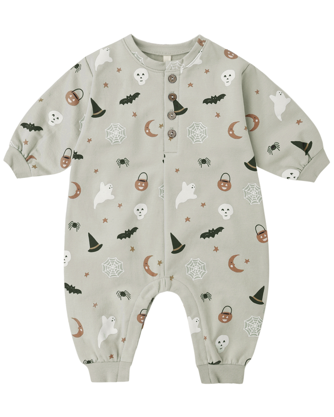 A long-sleeve baby romper in a light sage green color, decorated with a cute Halloween pattern of white ghosts, black bats, brown witch hats, jack-o'-lanterns, spiderwebs, and moons. It features a snap-button front and cuffed ankles.