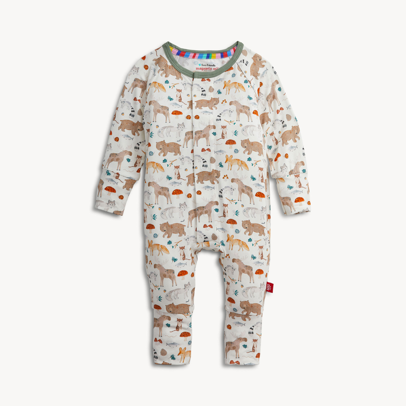 A baby long-sleeve footless one-piece jumpsuit with an all-over woodland animal print, featuring a white background with illustrations of deer, rabbits, foxes, and mushrooms. It has a colorful striped inner collar and a small red brand tag on the leg.