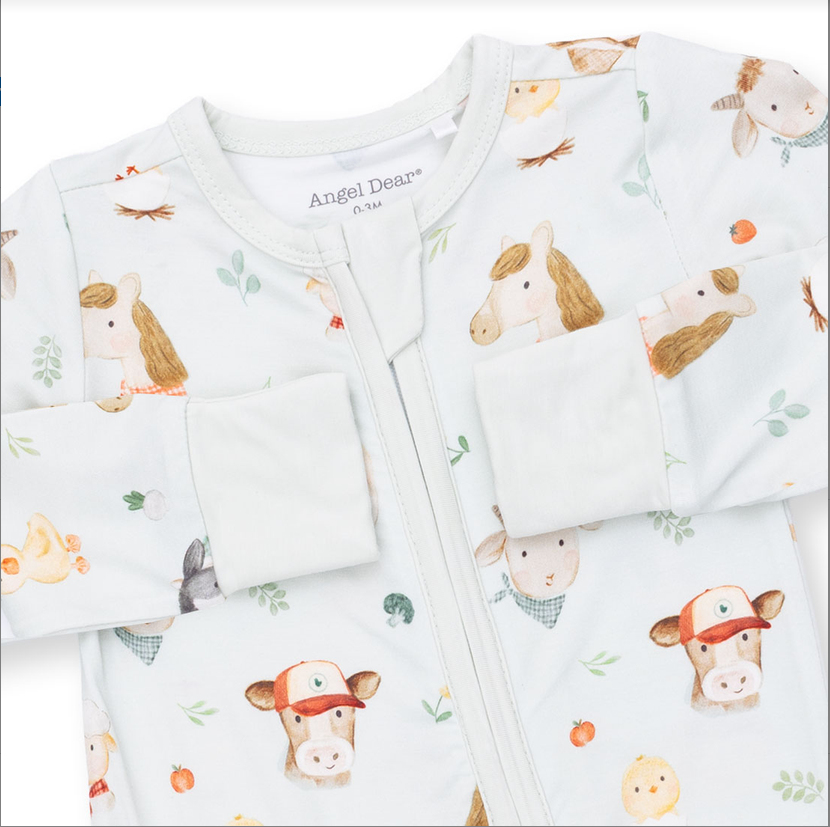 A baby zip-up sleeper by Angel Dears, featuring a white background with a colorful cartoon animal print of horses, chickens, ducks, and a donkey. The long sleeves are turned up, and the front zipper is fully visible.