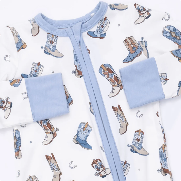 Baby outfit with blue pants and white shirt on a patterned background of cowboy boots and horseshoes.