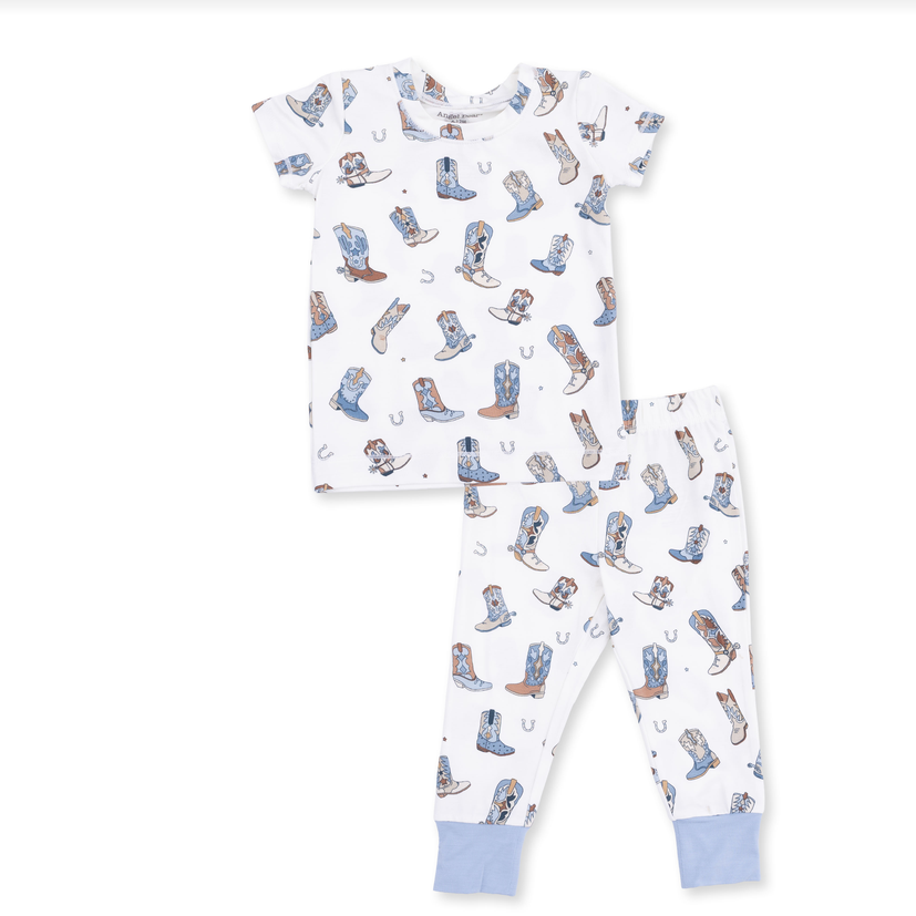 A two-piece children's pajama set featuring a short-sleeve top and matching pants, both in white with an all-over cowboy boot print in shades of blue, brown, and gray. The pants have light blue ribbed cuffs, and the set is photographed flat against a solid white background.
