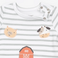 A close-up of a baby long-sleeve top with white and light gray horizontal stripes, featuring embroidered farm animal faces (pig and cow) and part of an orange barn on the front.