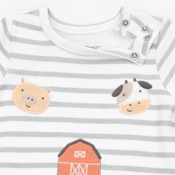 A close-up of a baby long-sleeve top with white and light gray horizontal stripes, featuring embroidered farm animal faces (pig and cow) and part of an orange barn on the front.
