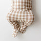 A baby footed sleeper or onesie in a beige and white gingham check pattern, shown from the back against a plain white background.