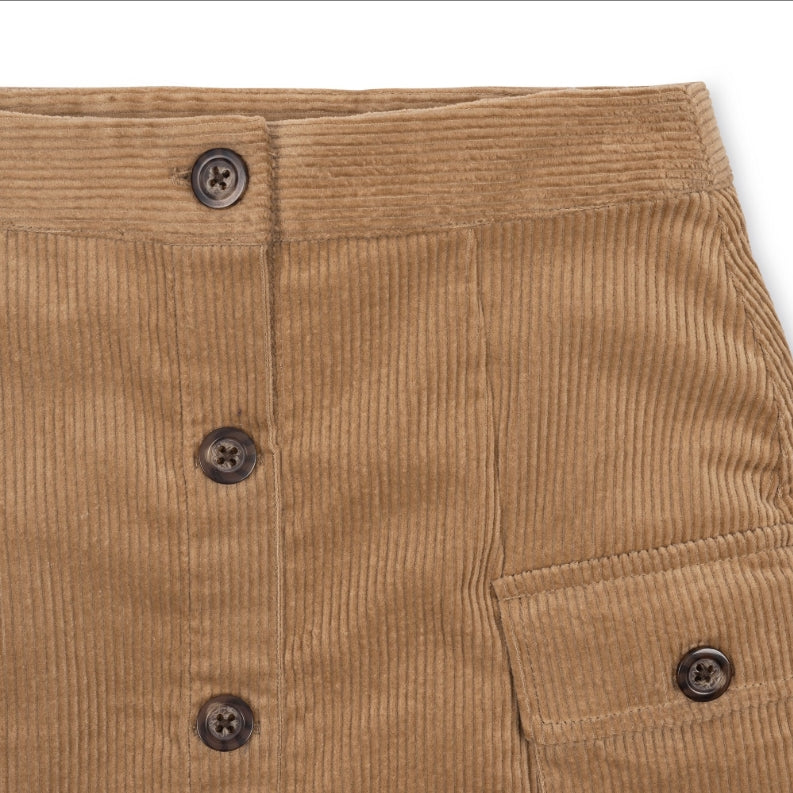 Close-up of a tan corduroy garment, likely a skirt or pants leg, showing the ribbed texture, dark buttons, and a side pocket on a white background.