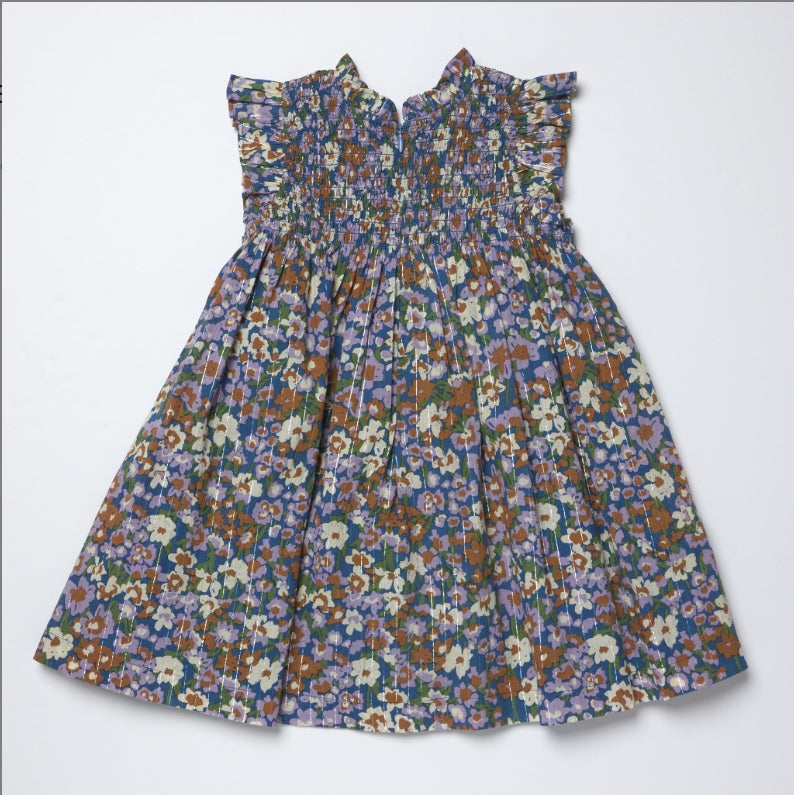 A sleeveless smocked dress with a dense multicolor floral print, featuring ruffled shoulder details and a gathered skirt, laid flat against a light gray background.