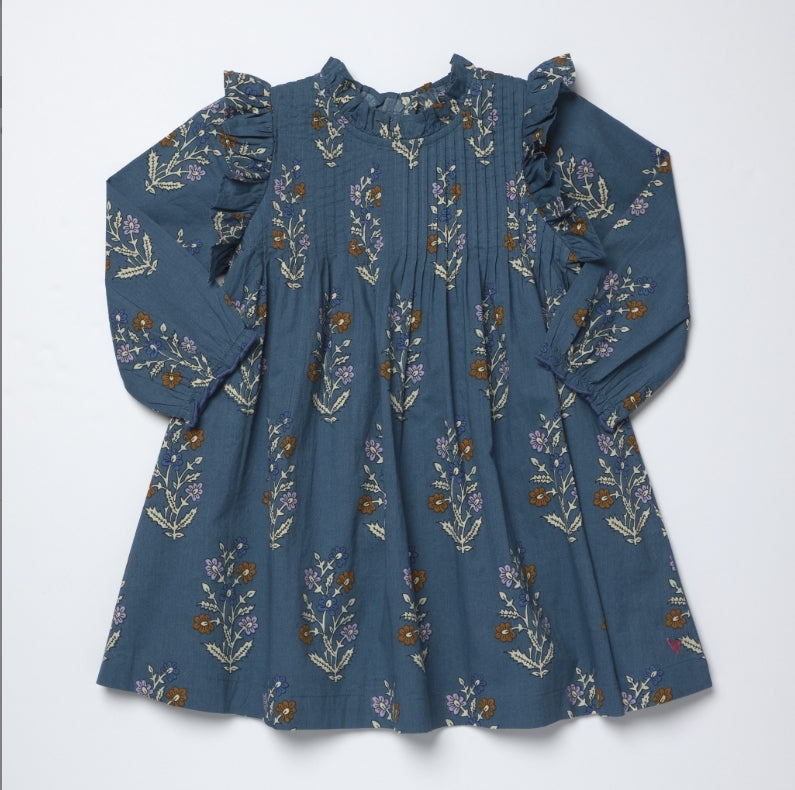 A long-sleeve blue-gray cotton dress with a delicate floral and botanical print in muted brown, purple, and beige tones, featuring ruffled shoulders and a gathered neckline, laid flat against a white background.
