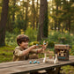 Child playing with a wooden archery set outdoors in a forest
