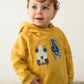 Child wearing a mustard yellow hoodie with car designs 