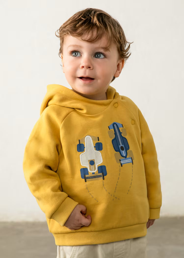 Child wearing a mustard yellow hoodie with car designs 