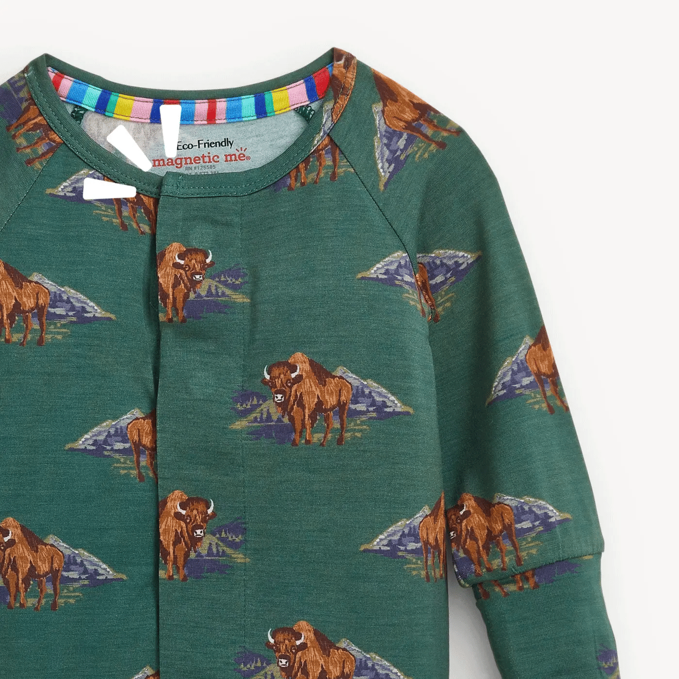A close-up of a children's long-sleeve top in dark green with an allover print of brown bison and purple mountain motifs. The inner collar features a colorful striped trim and a visible brand label reading 'Eco-Friendly magnetic me!'.