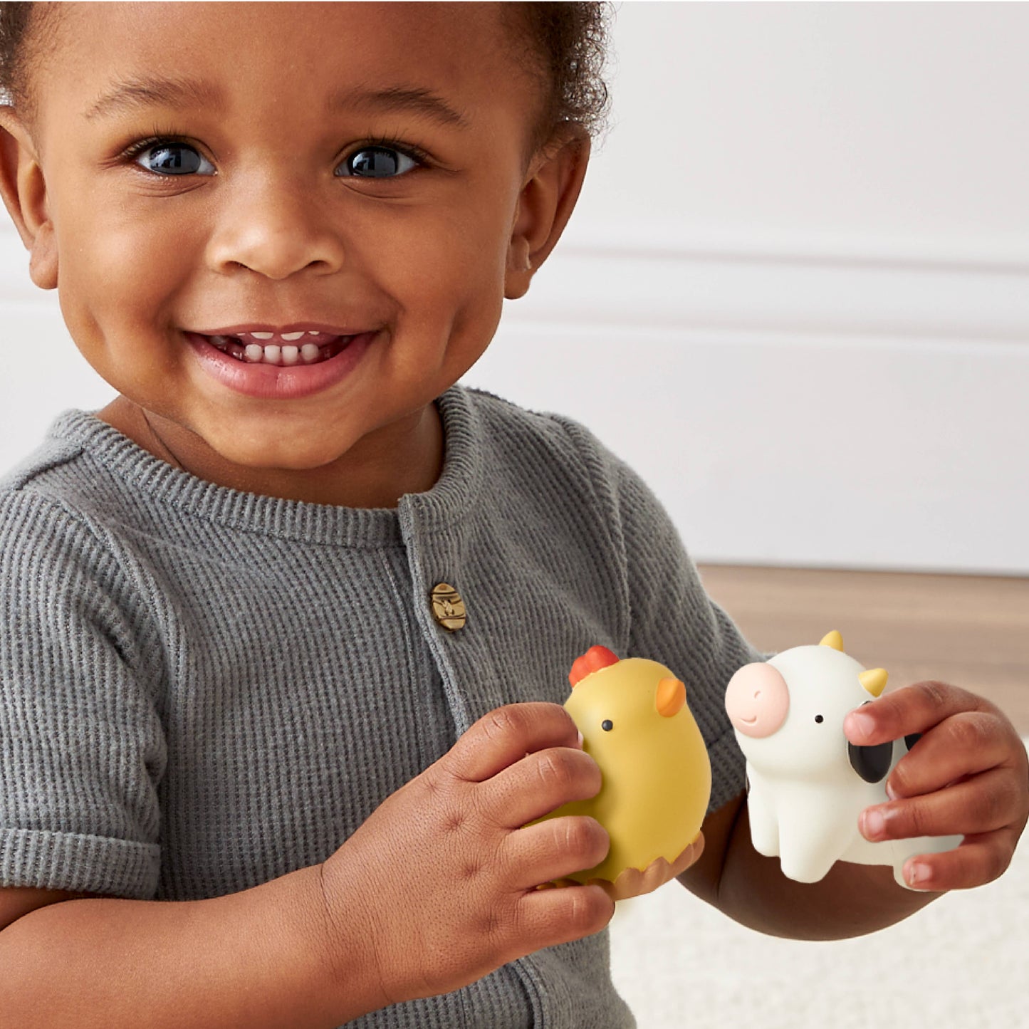 Child holding two toys, one yellow and one white, against a neutral background