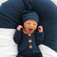 Newborn baby in a navy blue outfit with brown buttons