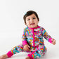 Child wearing a colorful onesie with cartoon characters on a white background